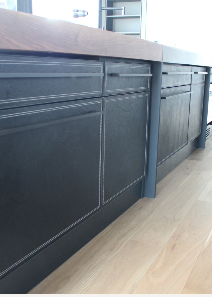 panneaux de tiroirs et d'armoire d'un ilot de cuisine recouverts en cuir avec surpiqures contrastées