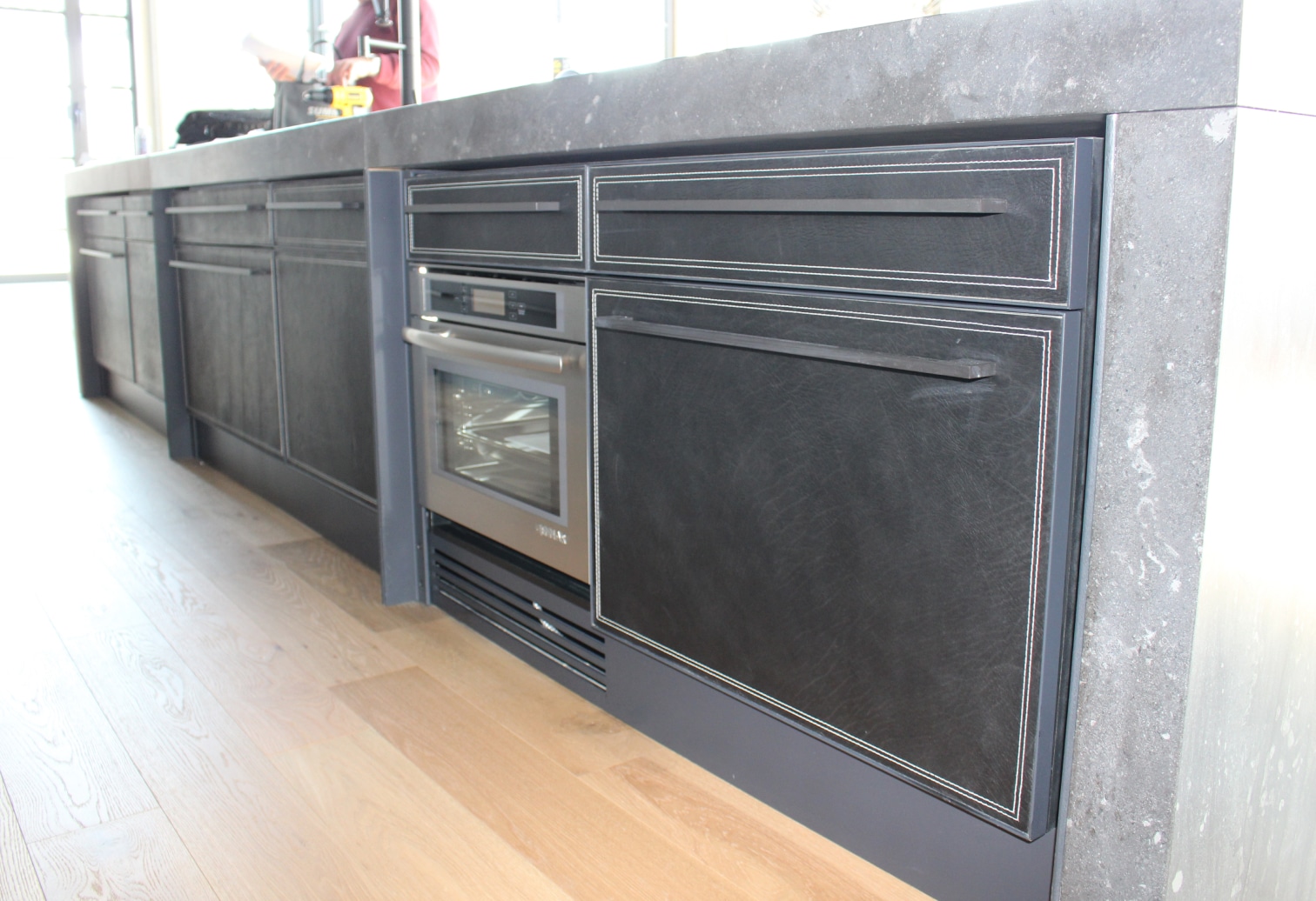 panneaux de tiroirs et d'armoire d'un ilot de cuisine recouverts en cuir avec surpiqures contrastées