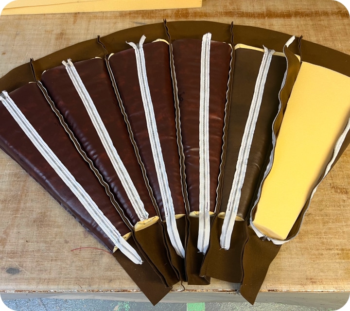 View of the back of a set of assembled and padded seam allowances. The end piece on the right is left open (zipper not closed) exposing the foam that can be seen in the other 5 pieces on the left.