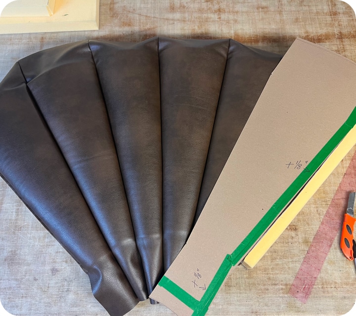 Front view of a set of assembled and upholstered seam constructions. The end piece on the right is covered with a template showing the shape of each piece of fabric creating each flute (tube) forming the rounded corner assembly.