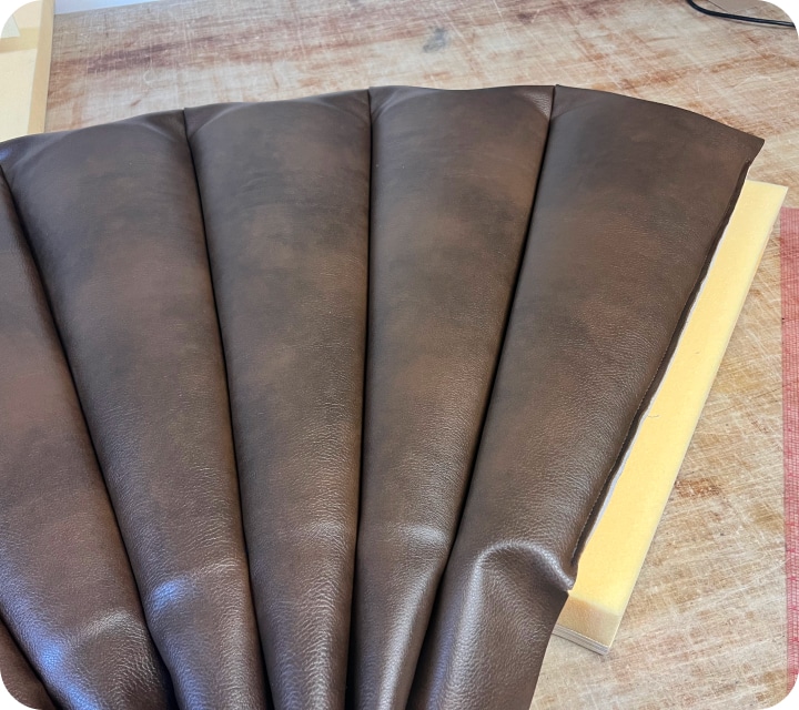 Close-up. View from the front of a set of assembled and padded seams. The right-hand end piece is open, revealing a partially uncovered piece of polyurethane foam.