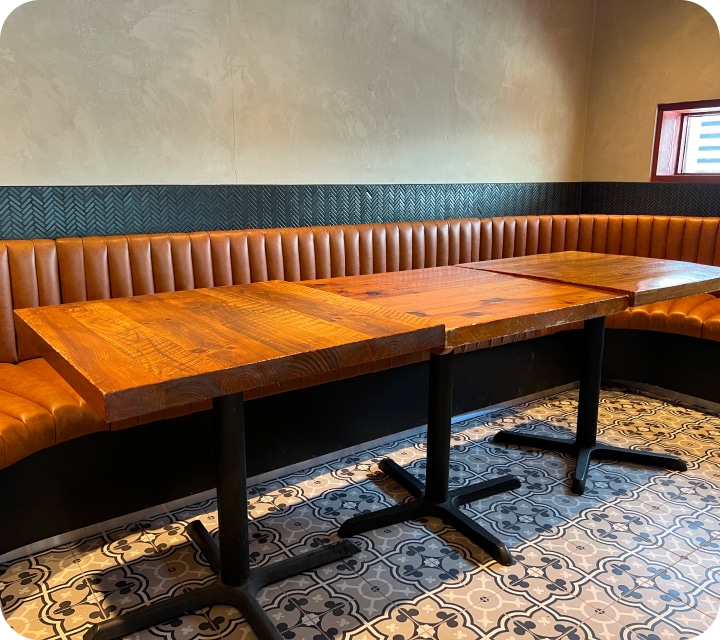 Partial side view of a restaurant dining room bench. The seat and back are made of padded and assembled flutes (tubes). Rounded corner. Caramel-colored faux leather. Bench custom-made according to customer choices and preferences. Réno-Montréal collaboration